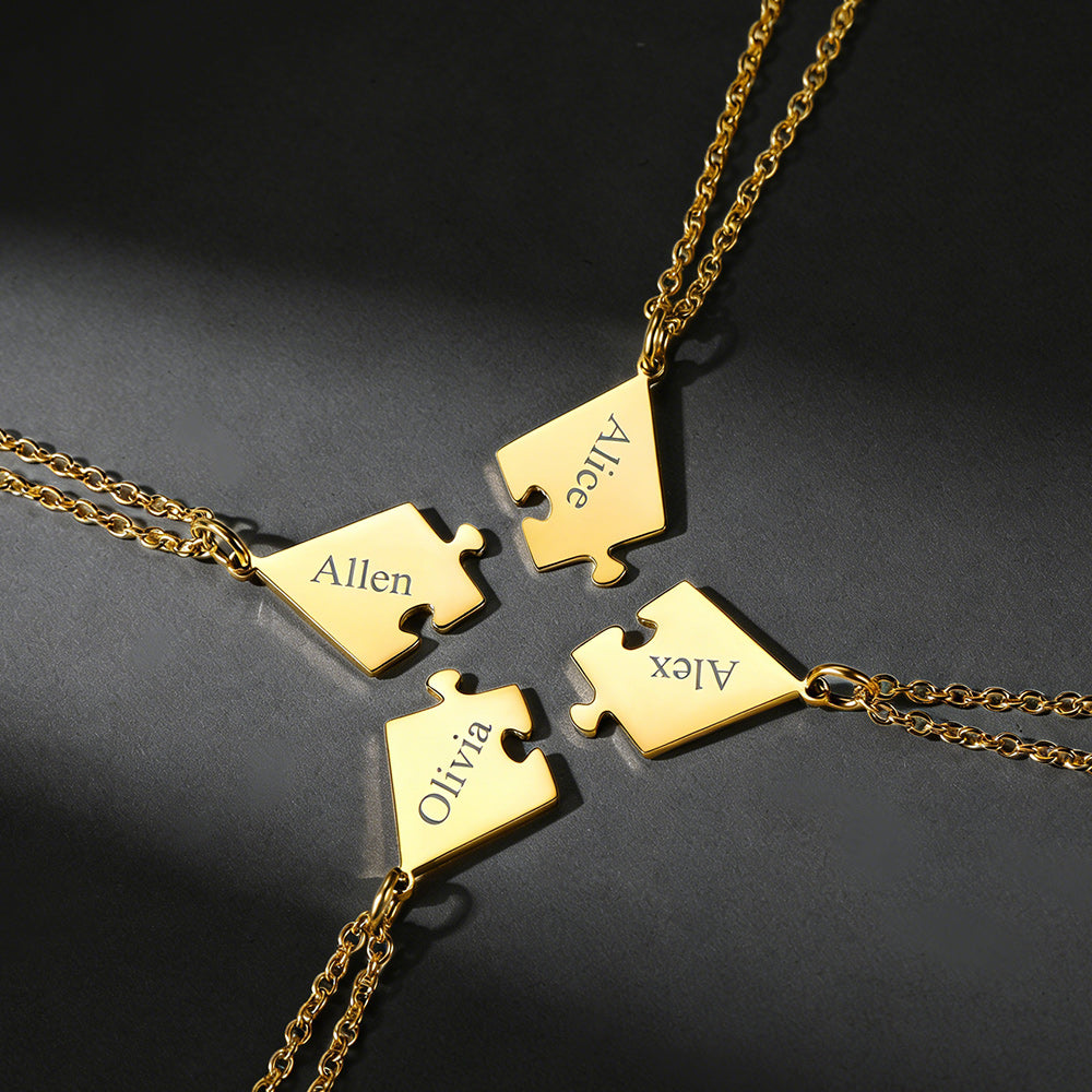 Gold puzzle piece necklaces with names engraved on a dark surface