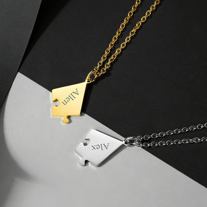 Two gold and silver puzzle piece pendants on chains against a black and gray background.