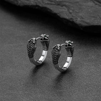 Pair of silver hoop earrings with snake designs on a dark surface