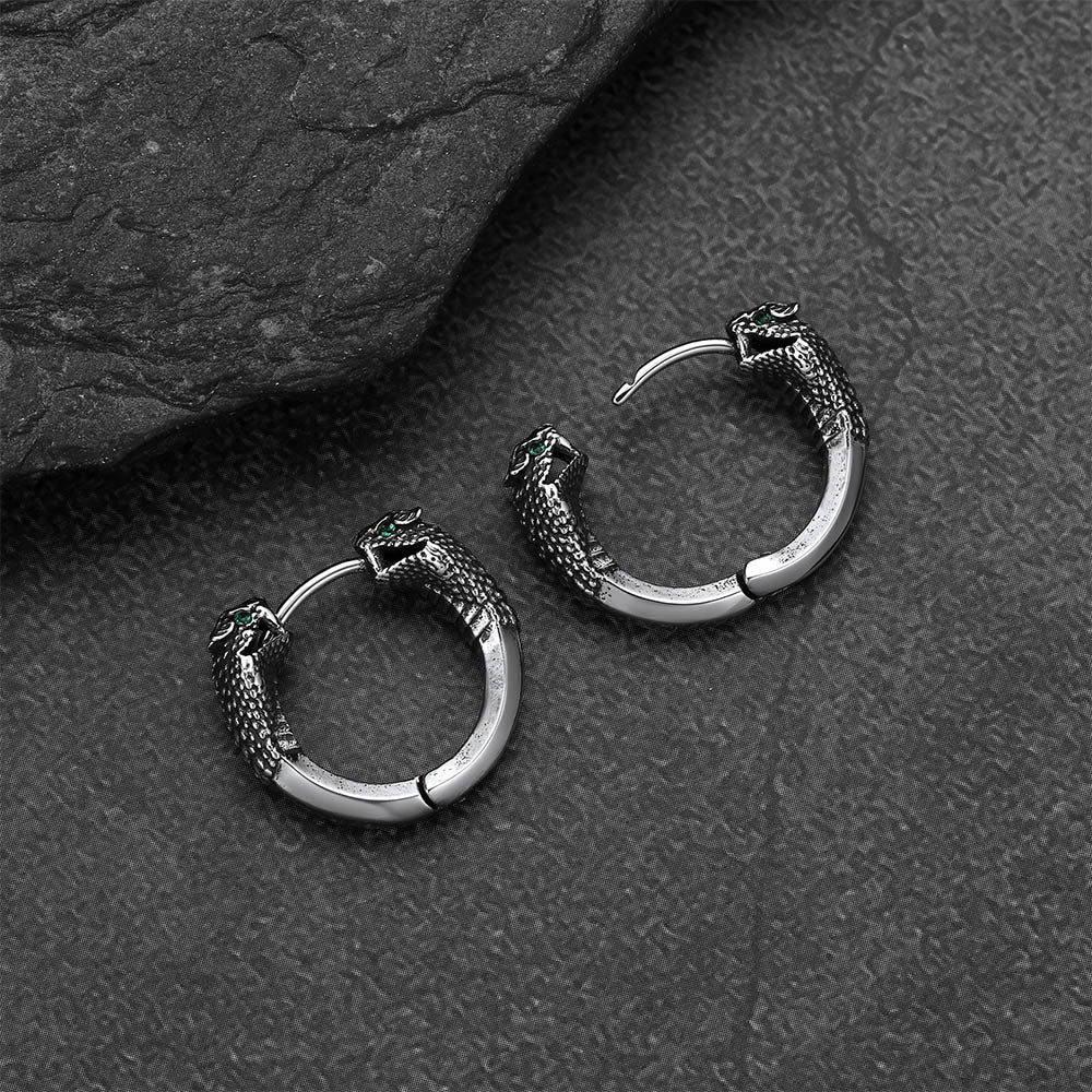 Silver hoop earrings with snake designs on a dark textured surface