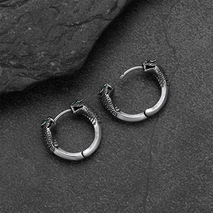 Silver hoop earrings with snake designs on a dark textured surface