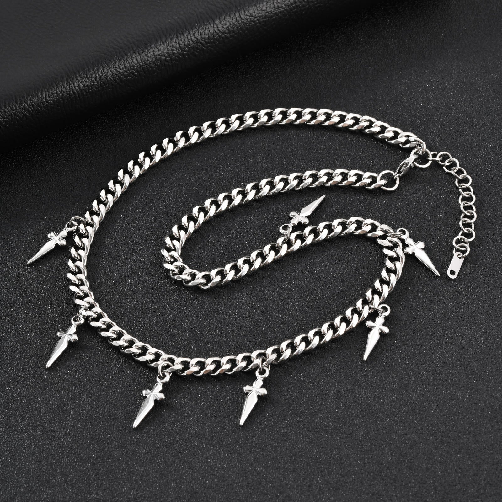 Silver chain anklets with spike charms on a dark surface