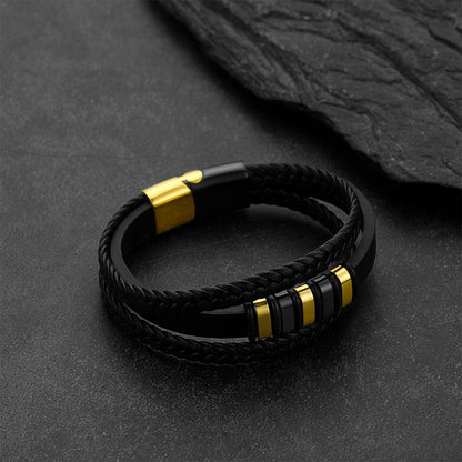 Gothic-style multi-layered leather bracelet against a dark gray rock background.