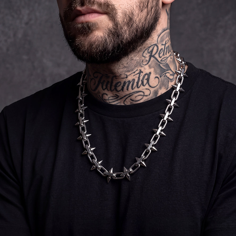Man wearing gothic punk thorn cone spike heavy chain necklace, side view,