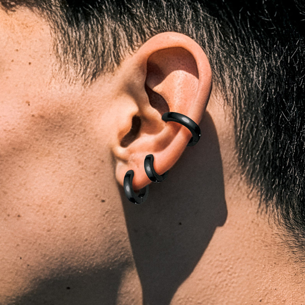 Close-up of an ear with black ear cuffs on a person with dark hair.