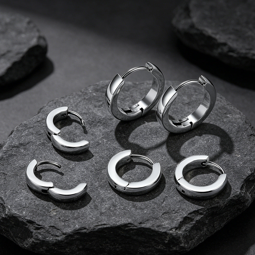 Set of silver hoop earrings on a dark stone surface