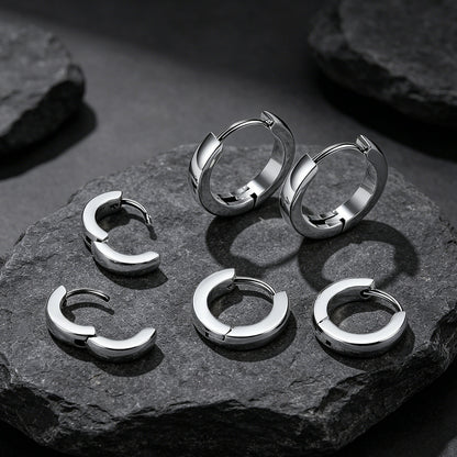 Set of silver hoop earrings on a dark stone surface