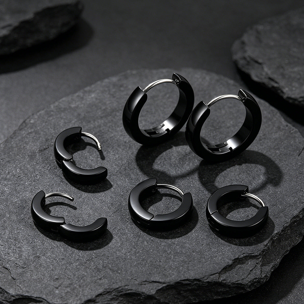 Set of black hoop earrings on a dark stone surface