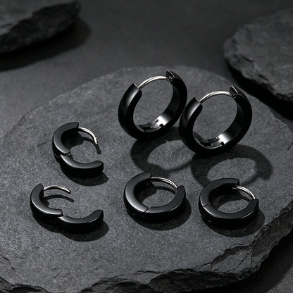 Set of black hoop earrings on a dark stone surface