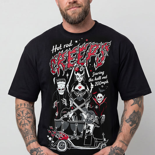 A man wearing a black graphic t-shirt with a detailed red, white, and black design featuring the text 'Hot rod GREEKY' and illustrations of a devil, Frankenstein's monster, and a skull car.img