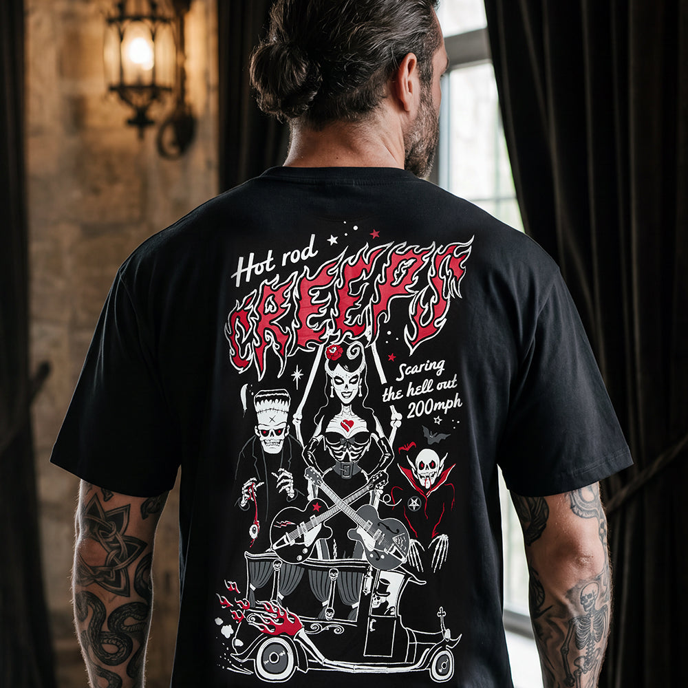 A man viewed from behind wearing a black graphic t-shirt with a large red and white horror-themed print on the back, set against a dark, moody interior background.