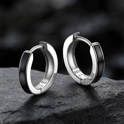 Pair of silver hoop earrings on a dark surface with a blurred background
