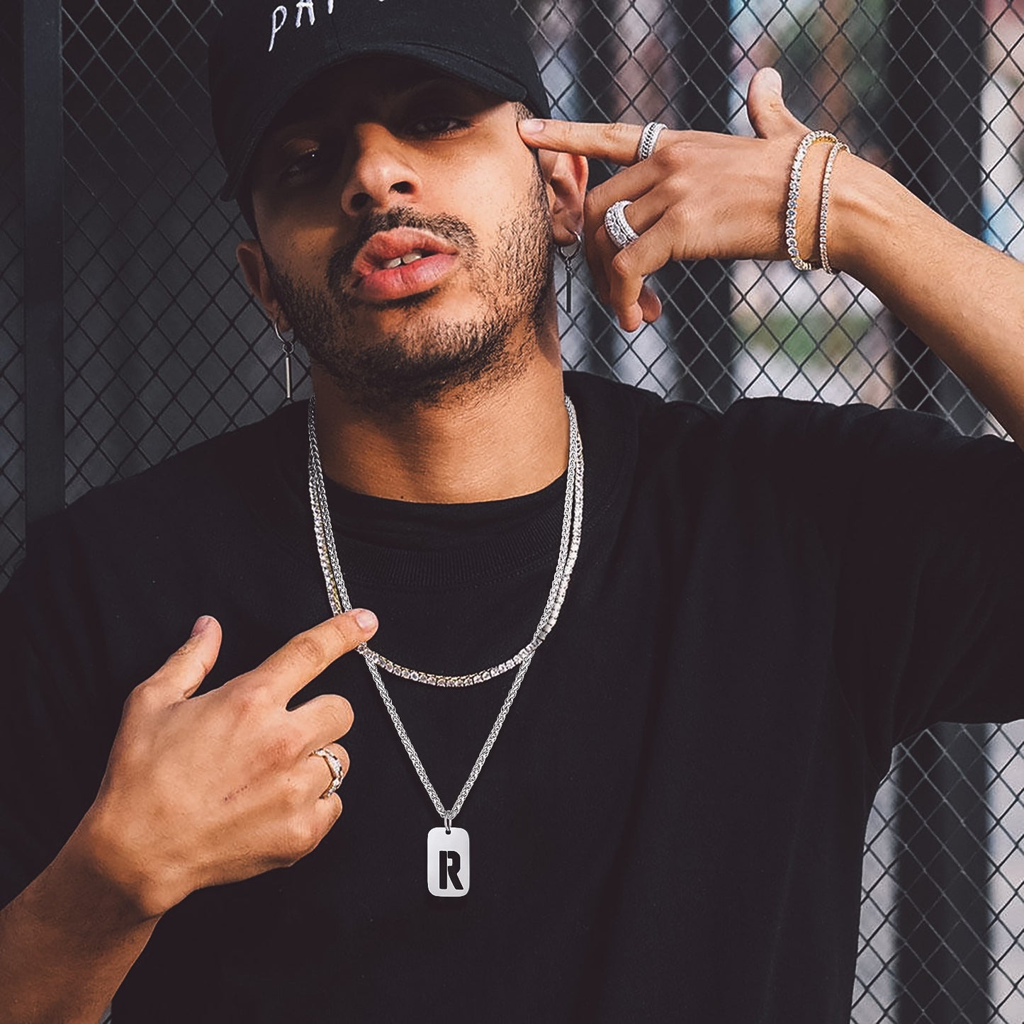 Man wearing personalized initial dog tag pendant necklace, with other jewelry