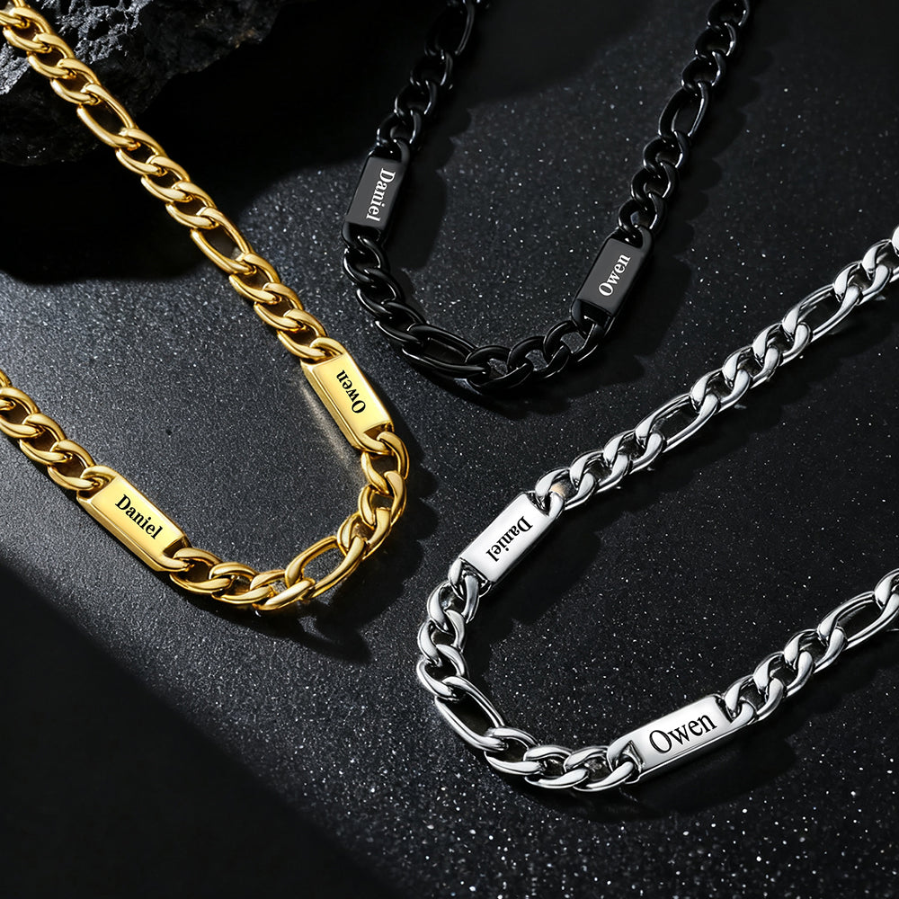 Three chain necklaces in gold, black, and silver on a dark surface.