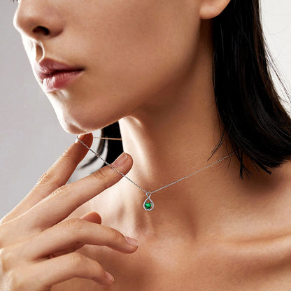 Woman wearing a necklace with a green gemstone pendant