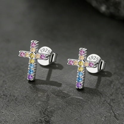 Cross-shaped earrings with colorful gemstones on a dark textured background