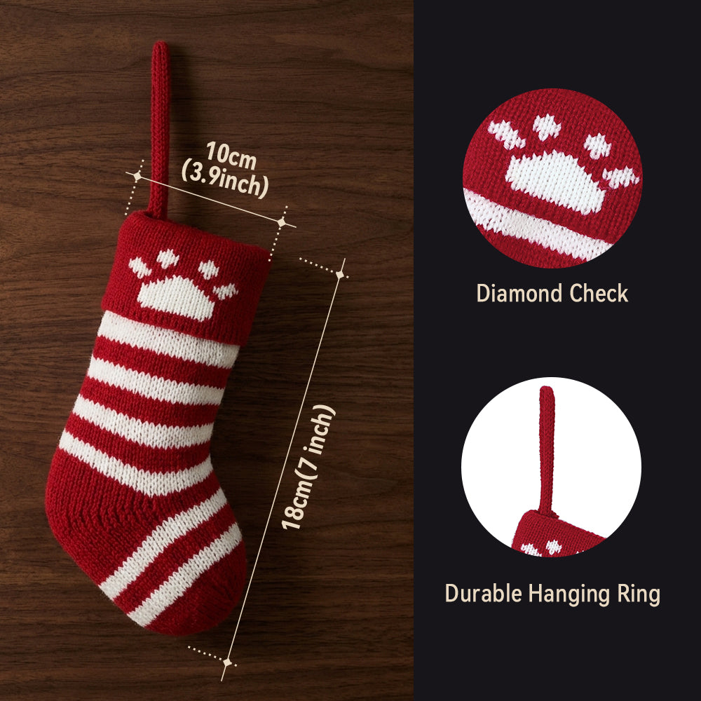 A red and white knitted Christmas stocking with a white paw print and diamond pattern.