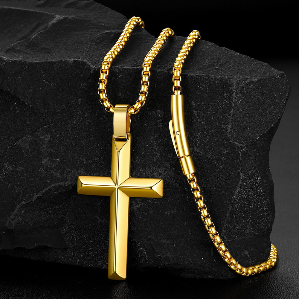 A gold beveled edge cross  pendant necklace displayed on a dark textured rock.