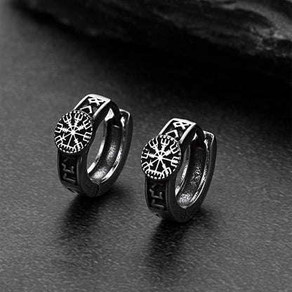 Pair of black hoop earrings with Norse Viking Compass on a dark surface
