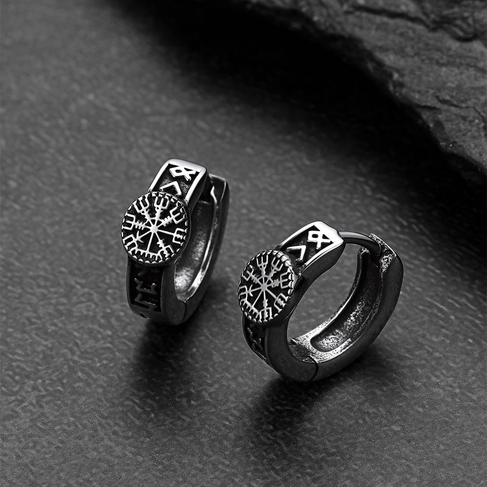 Pair of silver Viking-style hoop earrings on a dark textured surface