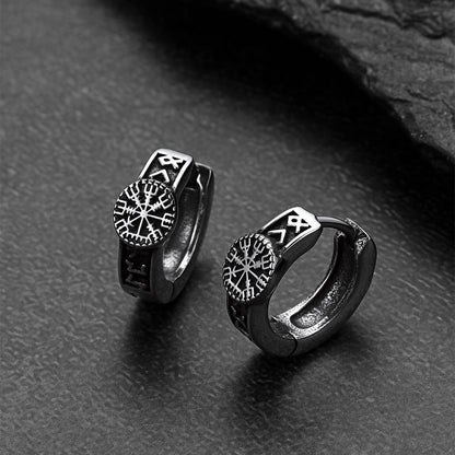 Pair of silver Viking-style hoop earrings on a dark textured surface