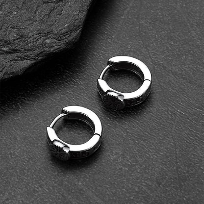 Pair of silver hoop earrings on a dark textured surface