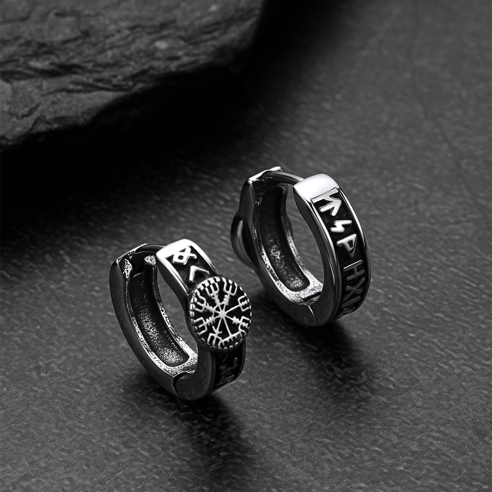 Pair of silver hoop earrings with engraved designs on a dark surface
