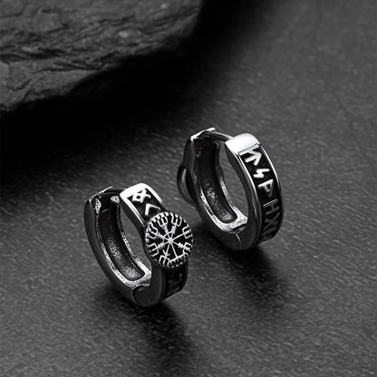 Pair of silver hoop earrings with engraved designs on a dark surface