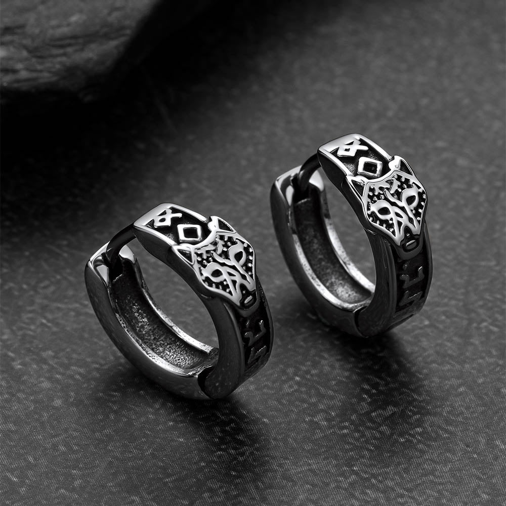 Pair of black hoop earrings with intricate designs on a dark textured surface