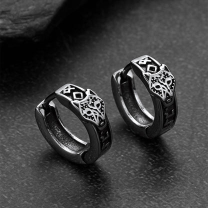 Pair of black hoop earrings with intricate designs on a dark textured surface