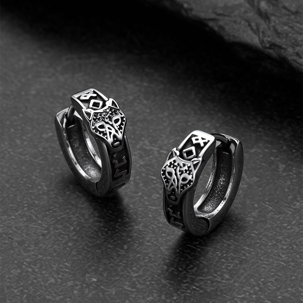 Pair of silver hoop earrings with intricate designs on a dark surface
