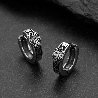 Pair of silver hoop earrings with intricate designs on a dark surface