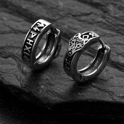 Pair of silver hoop earrings with intricate designs on a dark stone surface
