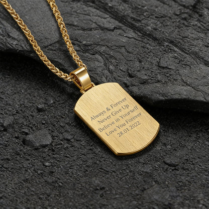 Gold pendant necklace with engraved text on a dark stone surface