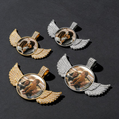 Four angel wing pendants with different gold and silver finishes on a dark background.