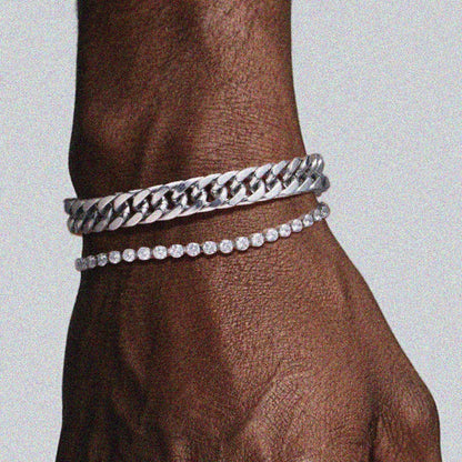 Close-up of a wrist wearing multiple silver bracelets on a light gray background