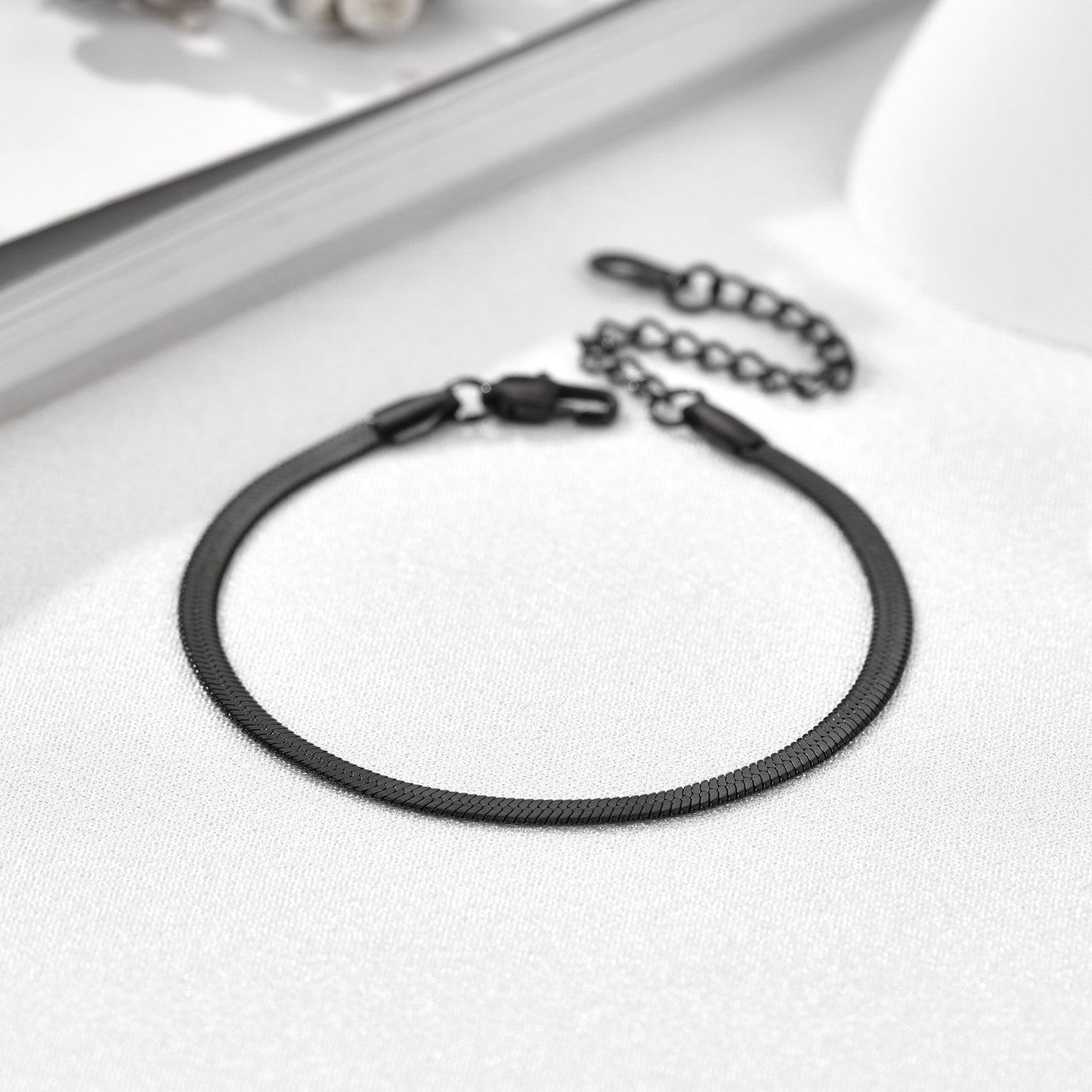 Black leather bracelet with metal clasp on a white surface