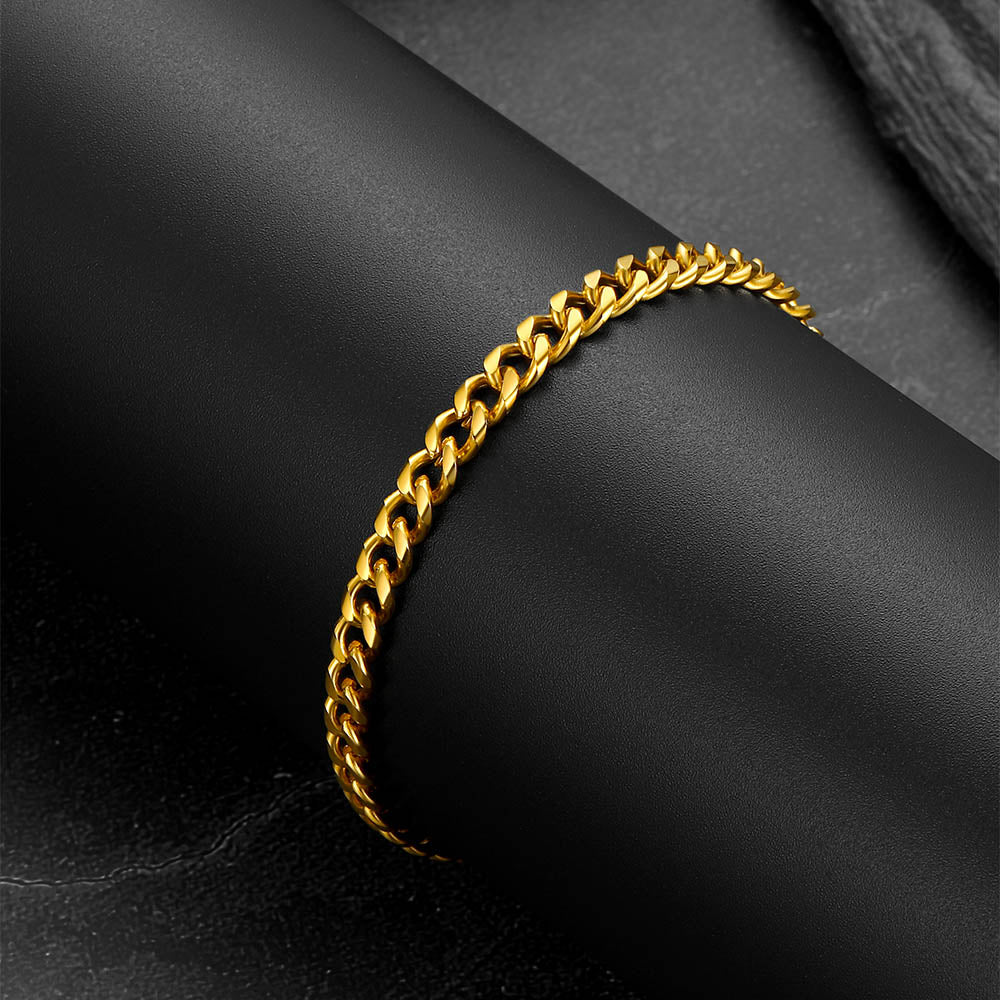 Gold chain bracelet on a dark fabric background