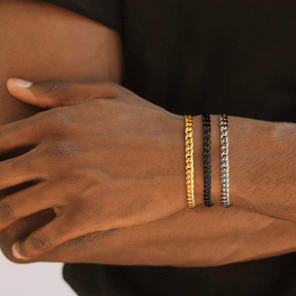 Close-up of a person's wrist wearing three gold and black chain bracelets.
