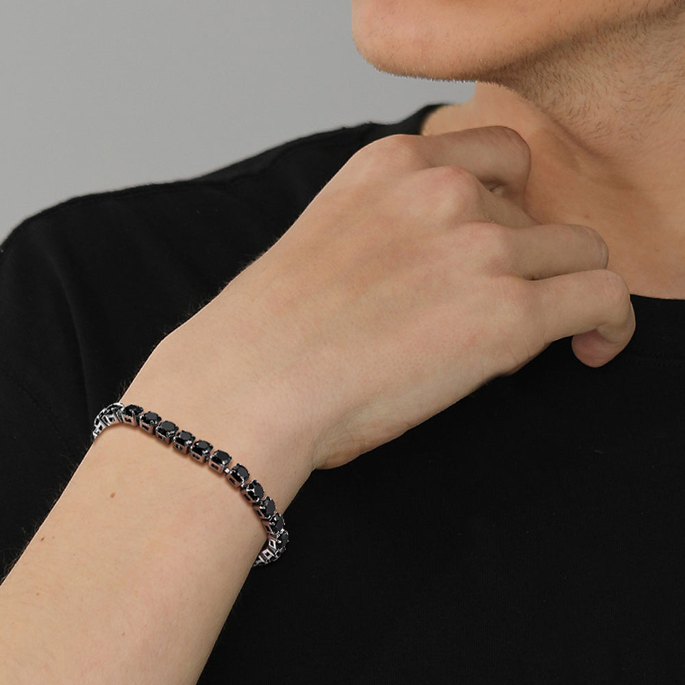 Person wearing a black bracelet on a plain background