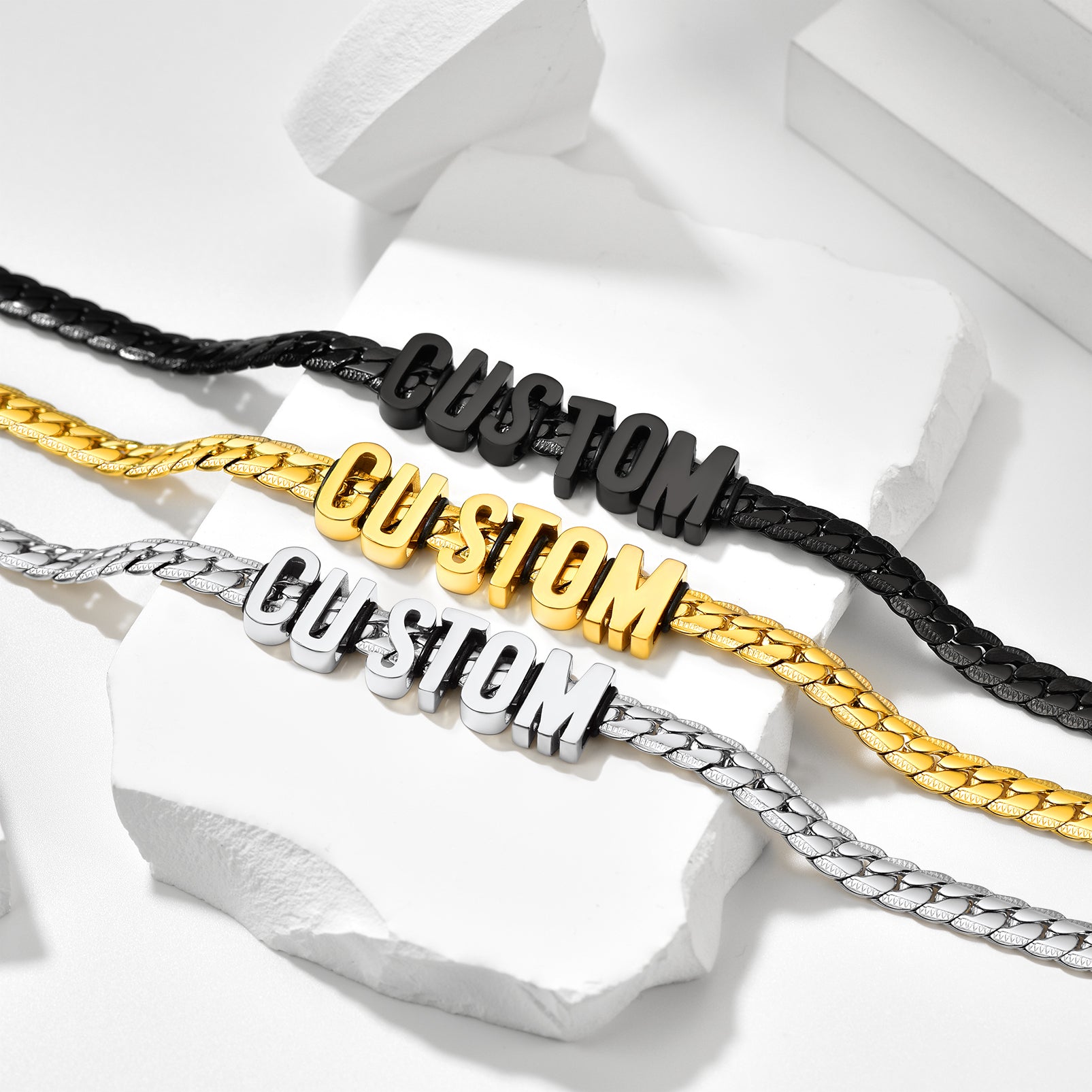 Three customizable bracelets in gold, silver, and black on a white background