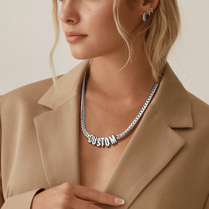 Person wearing a silver necklace with 'CUSTOM' pendant against a neutral background