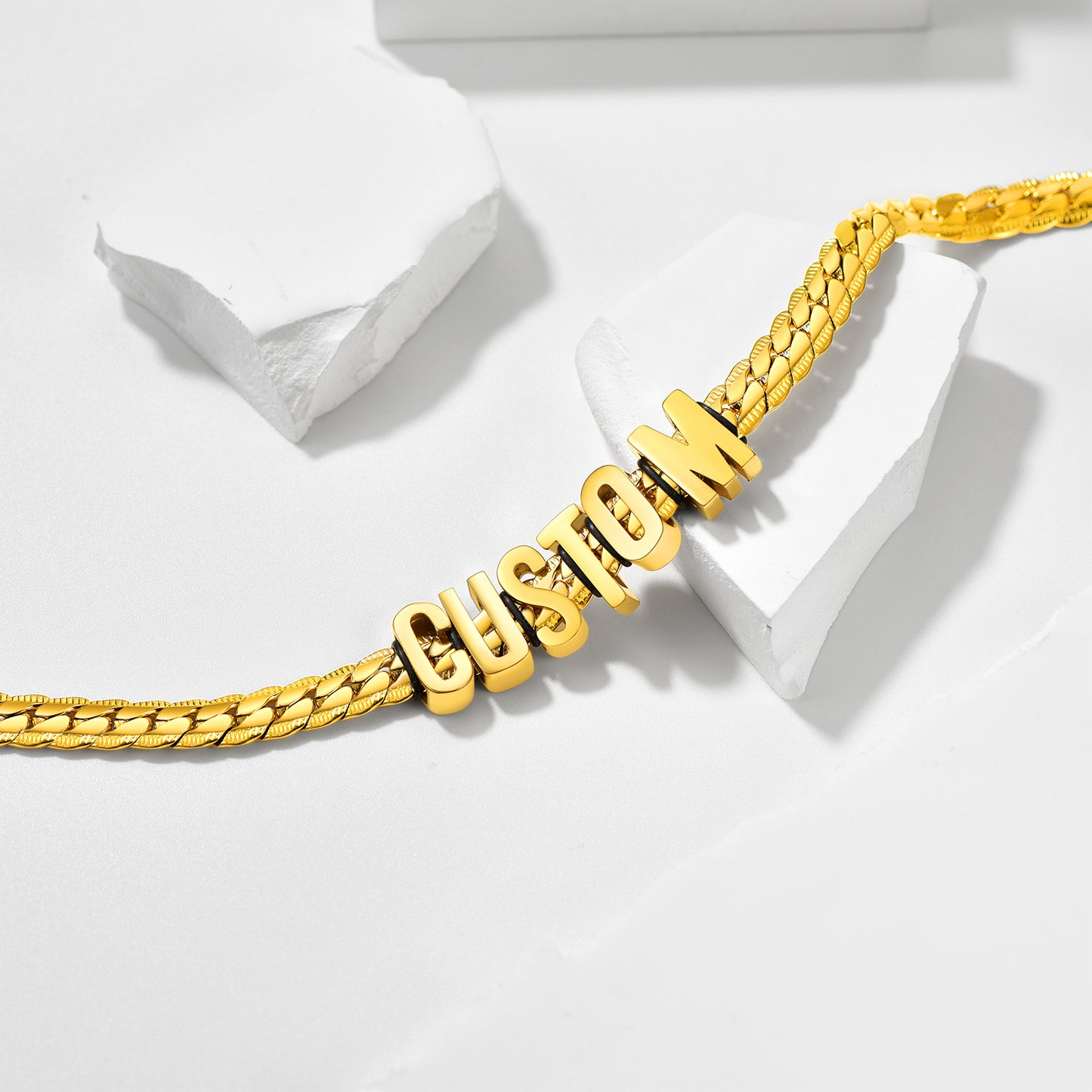 Gold chain bracelet with 'CUSTOM' letters on a white background