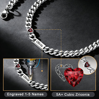 Silver bracelet with engraved name and red heart-shaped gemstone on a dark background