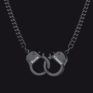 A black metal chain necklace with a pendant shaped like two interlocking handcuffs. 
