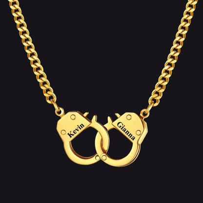 A gold-tone chain necklace with a customized handcuff pendant engraved with names.