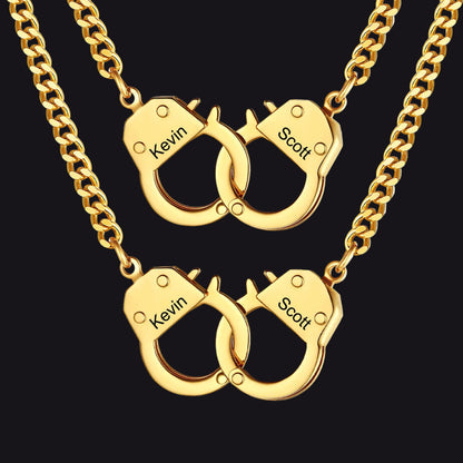 Two gold-toned chain necklaces with interlocking handcuff-shaped pendants.