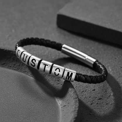 A black braided leather bracelet with silver cube letter beads spelling 'CUSTOM'.