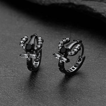 Pair of black Poseidon Trident Greek  hoop earrings on a dark surface
