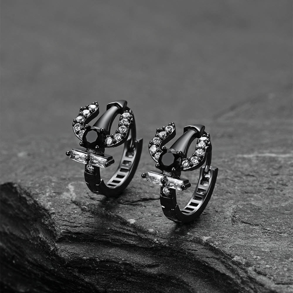 Pair of black Poseidon Trident Greek hoop earrings on a dark stone surface